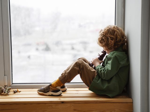 Immagine di un bambino che guarda dalla finestra con vetro trasparente|||